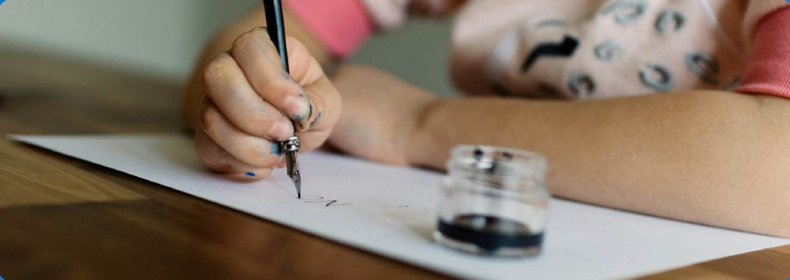 Child writing a letter by hand with ink and pen.